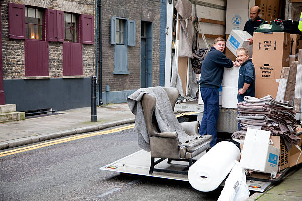 London, United kingdom- October 31, 2013: Removal men empty a van in London. Removal companies help people relocate their goods when moving house.